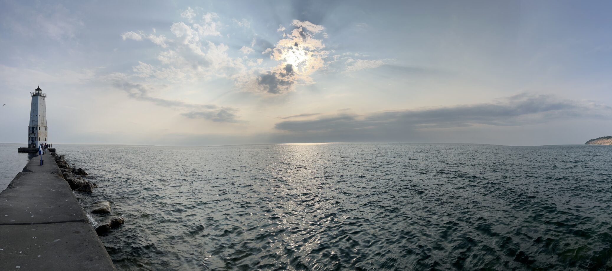 A lighthouse standing alone in Lake Michigan during the sunset.